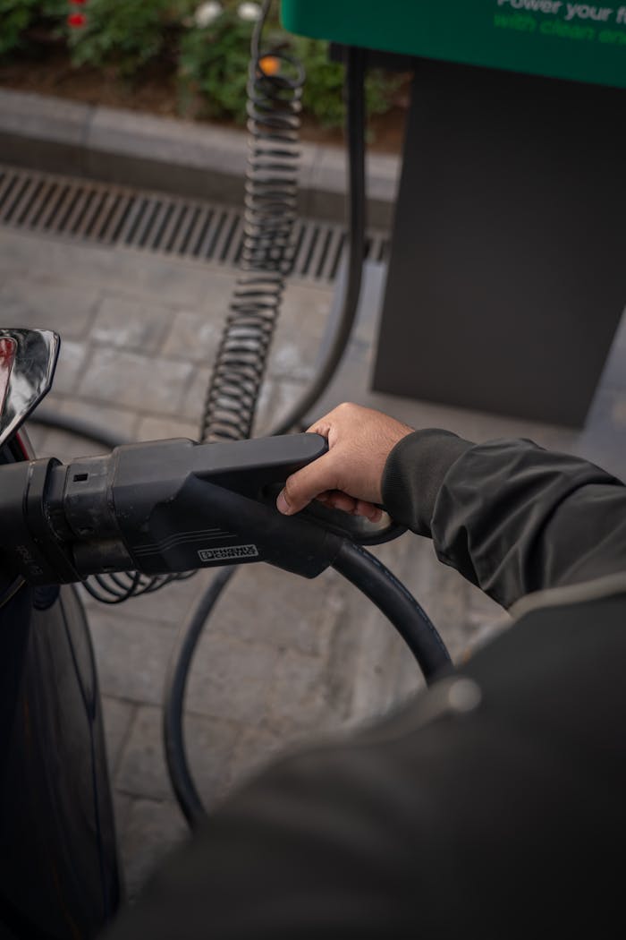 Close-up of a person charging an electric car at an outdoor station.